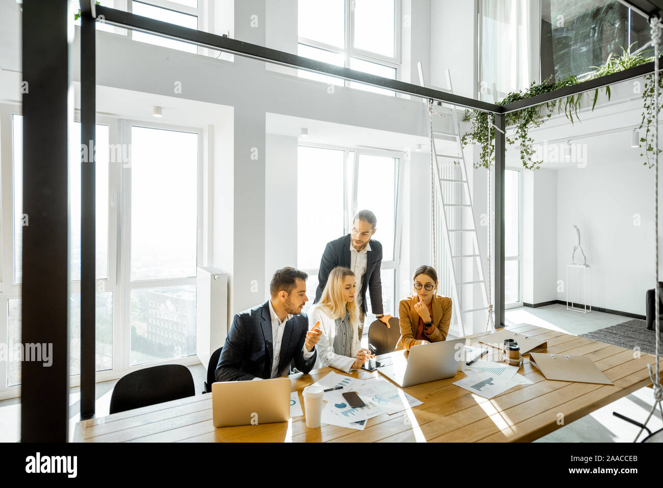 Group of a young office employees having some office work at the large  meeting table, wide view on the spacious room with large windows Stock  Photo - Alamy