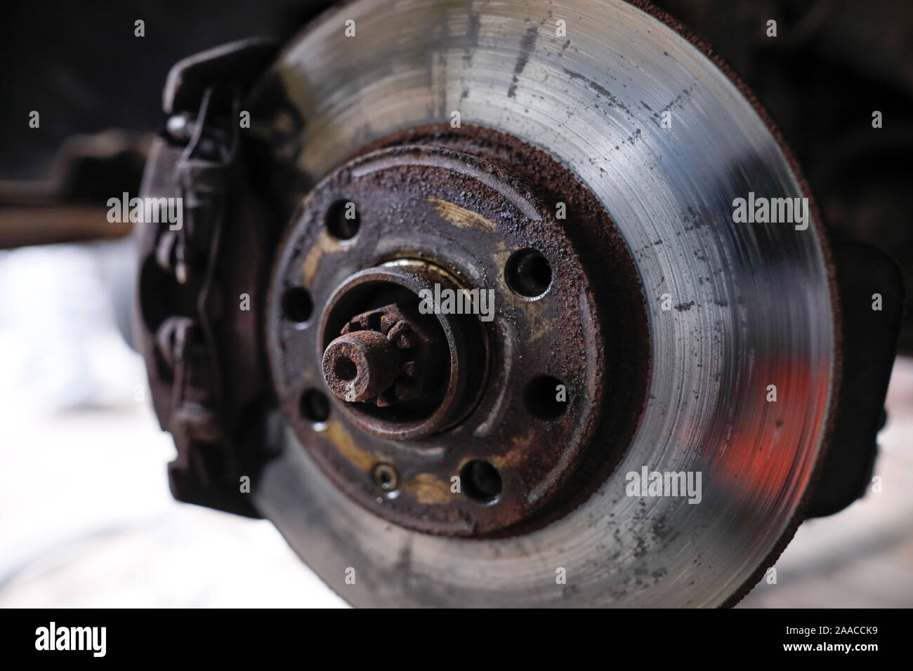 Shallow depth of field (selective focus) image with details of a rusty front disc brake of a car. Stock Photo