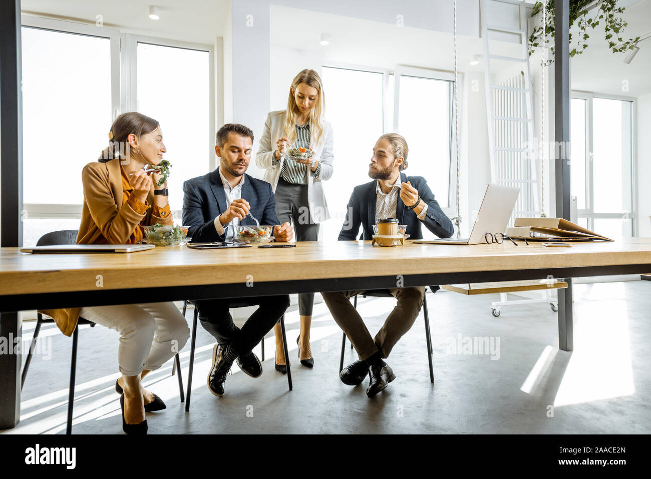 Group of a young office workers eating salads and drinking coffee at the modern office canteen