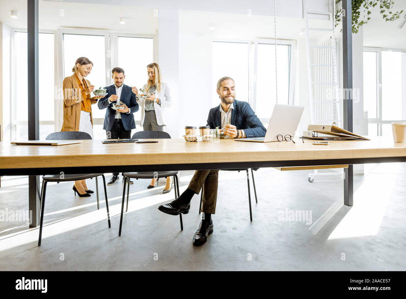 Group of a young office workers eating salads and drinking coffee at