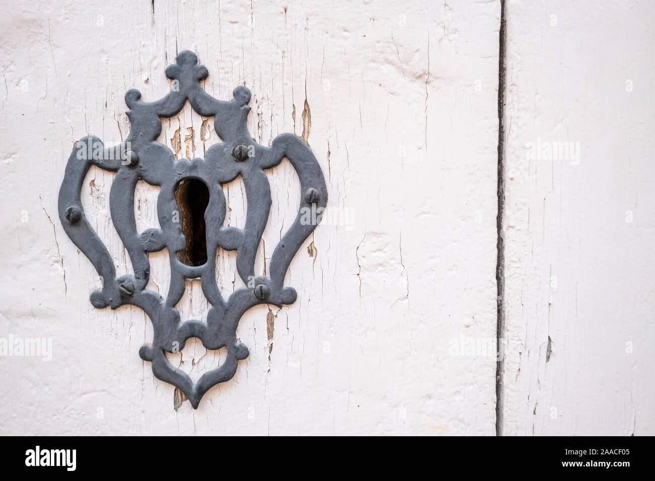 close up photo of a keyhole with a decorated key plate with screws on a white painted old door, copy space Stock Photo