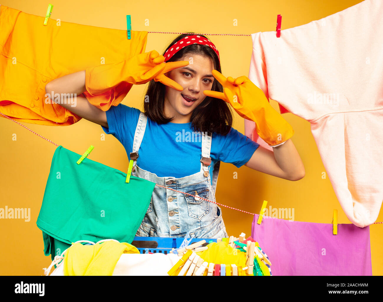 Funny and beautiful housewife doing housework isolated on yellow ...