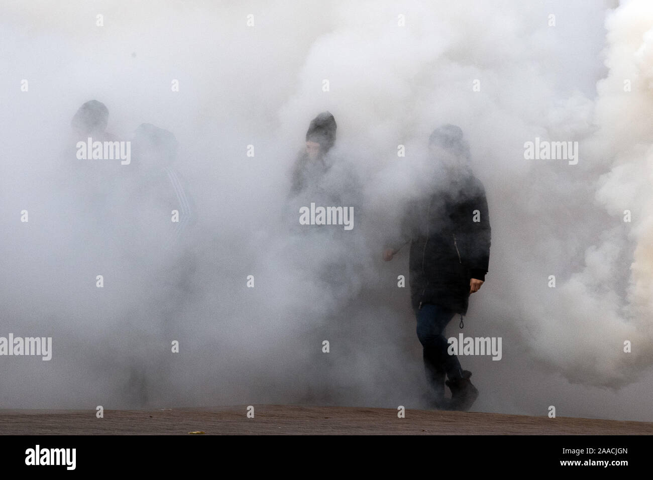 Leverkusen, Germany. 21st Nov, 2019. Policemen disguised as football fans walk through smoke. Again and again police officers have to do with aggressive football fans, at Bundesliga matches there are often hundreds of people on the spot. The emergency forces in Leverkusen have rehearsed what to pay particular attention to during such missions. Credit: Federico Gambarini/dpa/Alamy Live News Stock Photo
