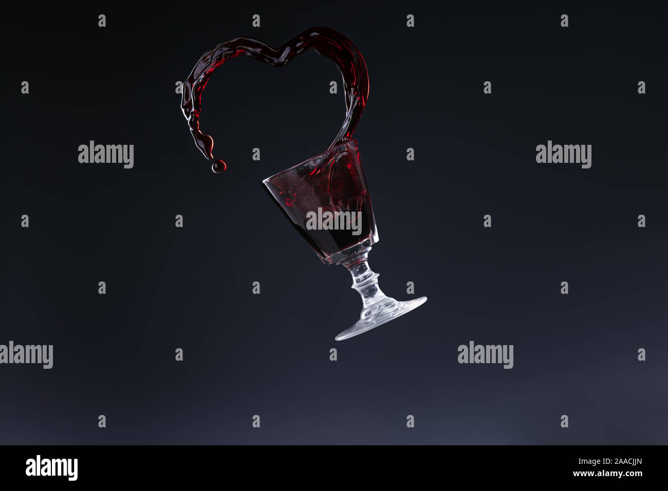 Projection of red wine in the shape of a heart on dark background Stock Photo