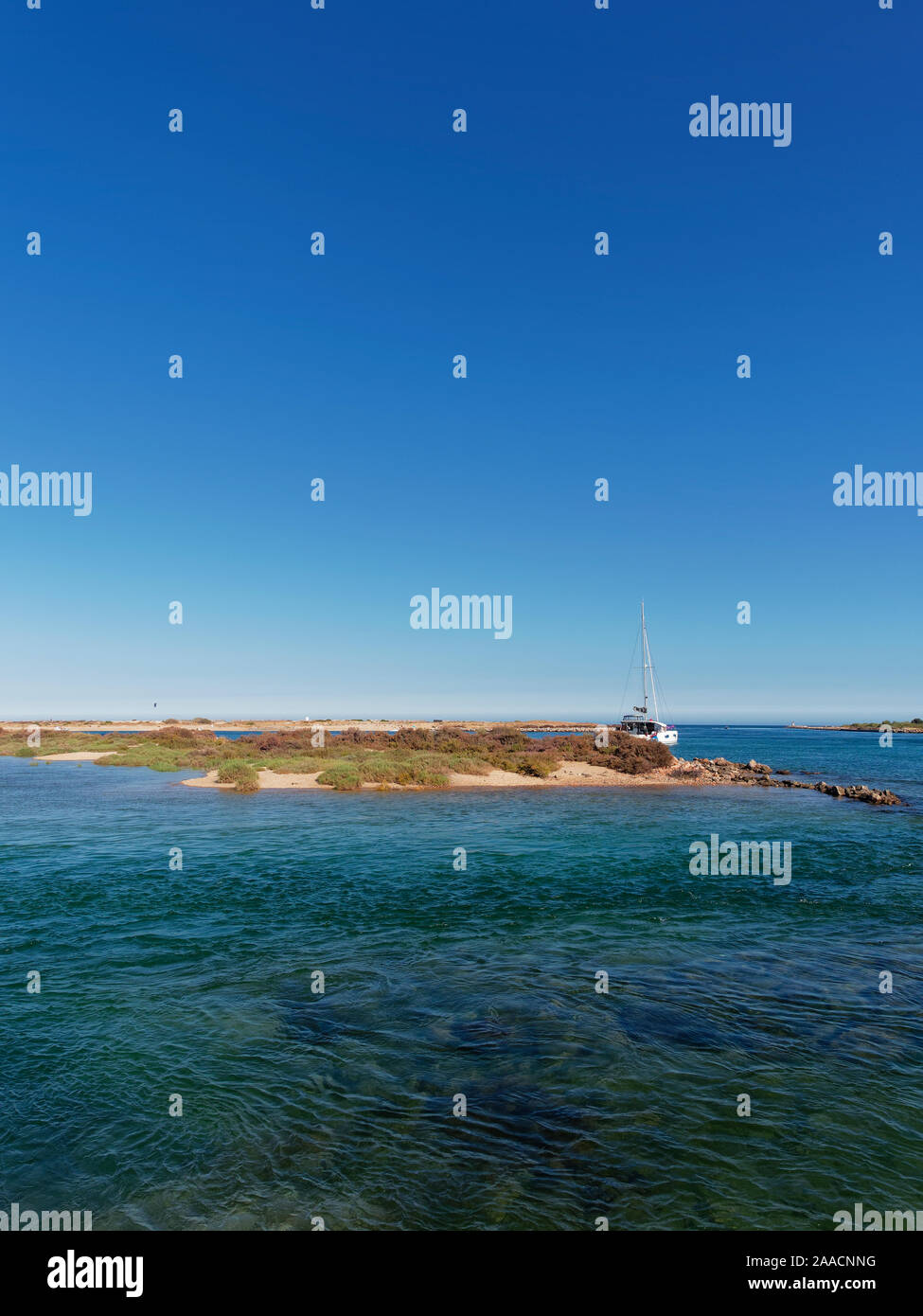 A catamaran moored within one of the small Bays between the various Islands of Ilha da Culatra on the Algarve Coast of Portugal. Stock Photo