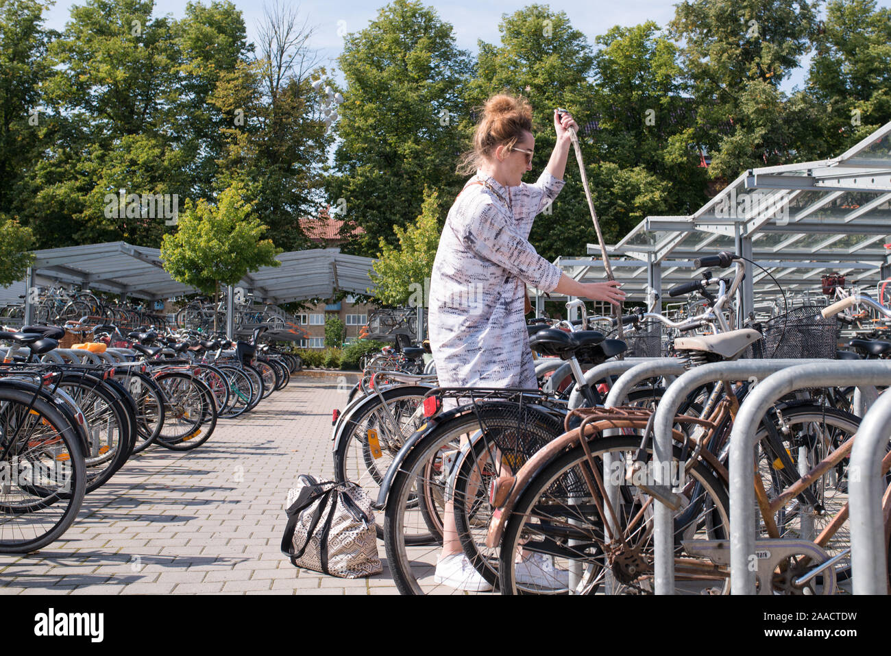 hip woman unlocking her bike from bicycle stand in summer Stock Photo