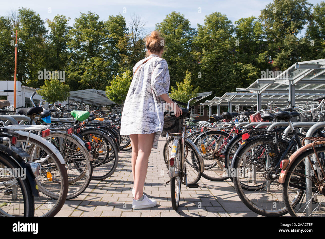 hip woman unlocking her bike from bicycle stand in summer Stock Photo