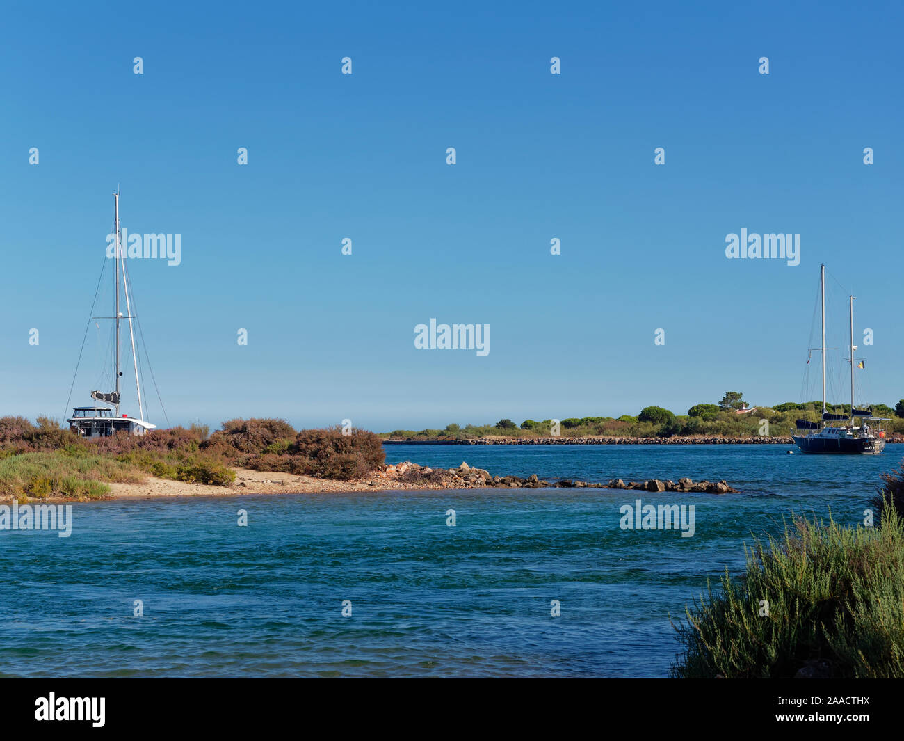 Yachts moored between the Islands of Ilha Da Culatra off the Portuguese Algarve Coast on a sunny, hot July afternoon. Stock Photo
