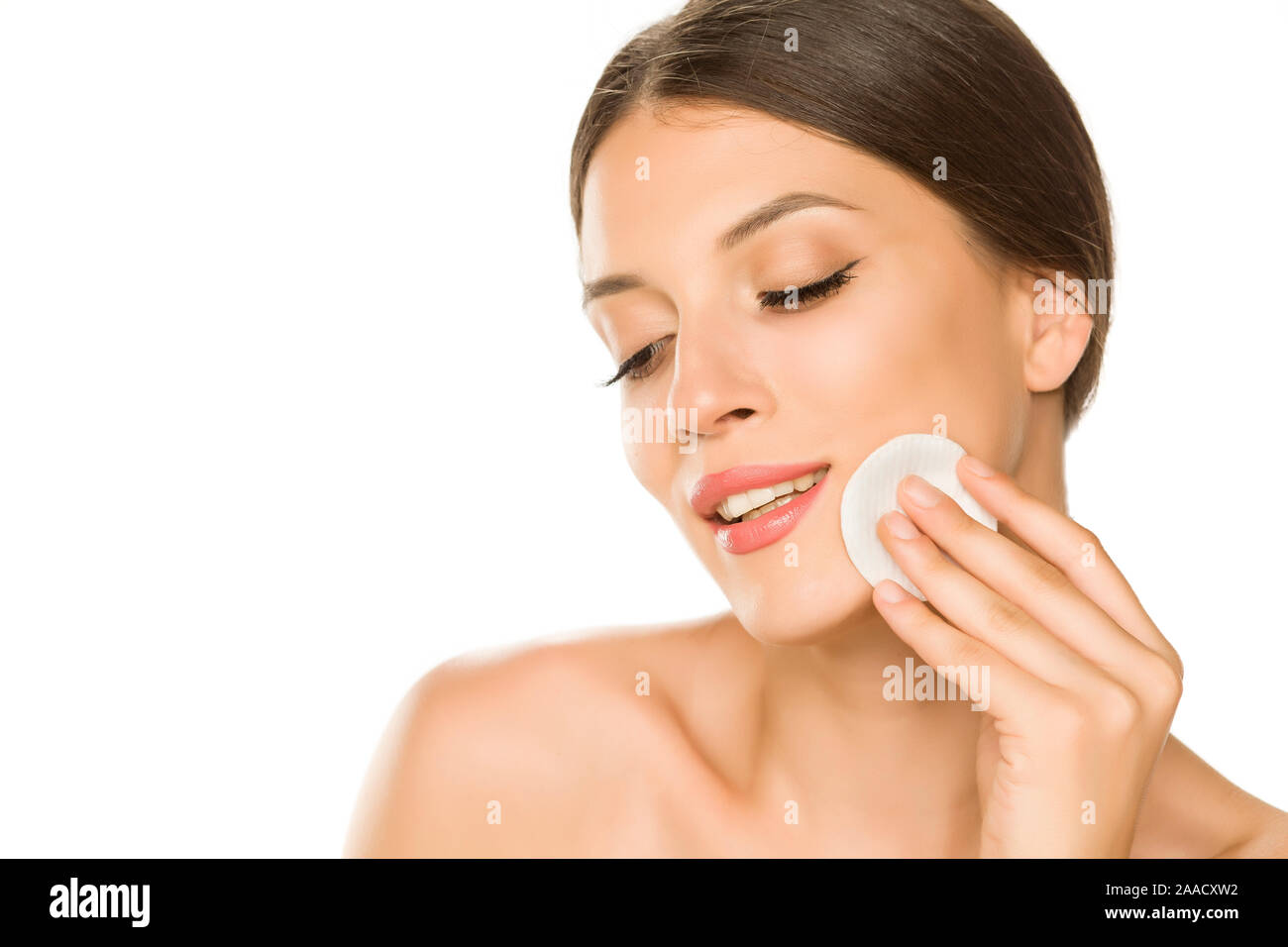 Young beautiful woman claning her face with cotton pad on white background Stock Photo