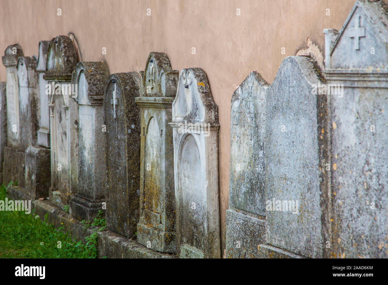 tombstones along the church wall with focus on the middle two Stock Photo