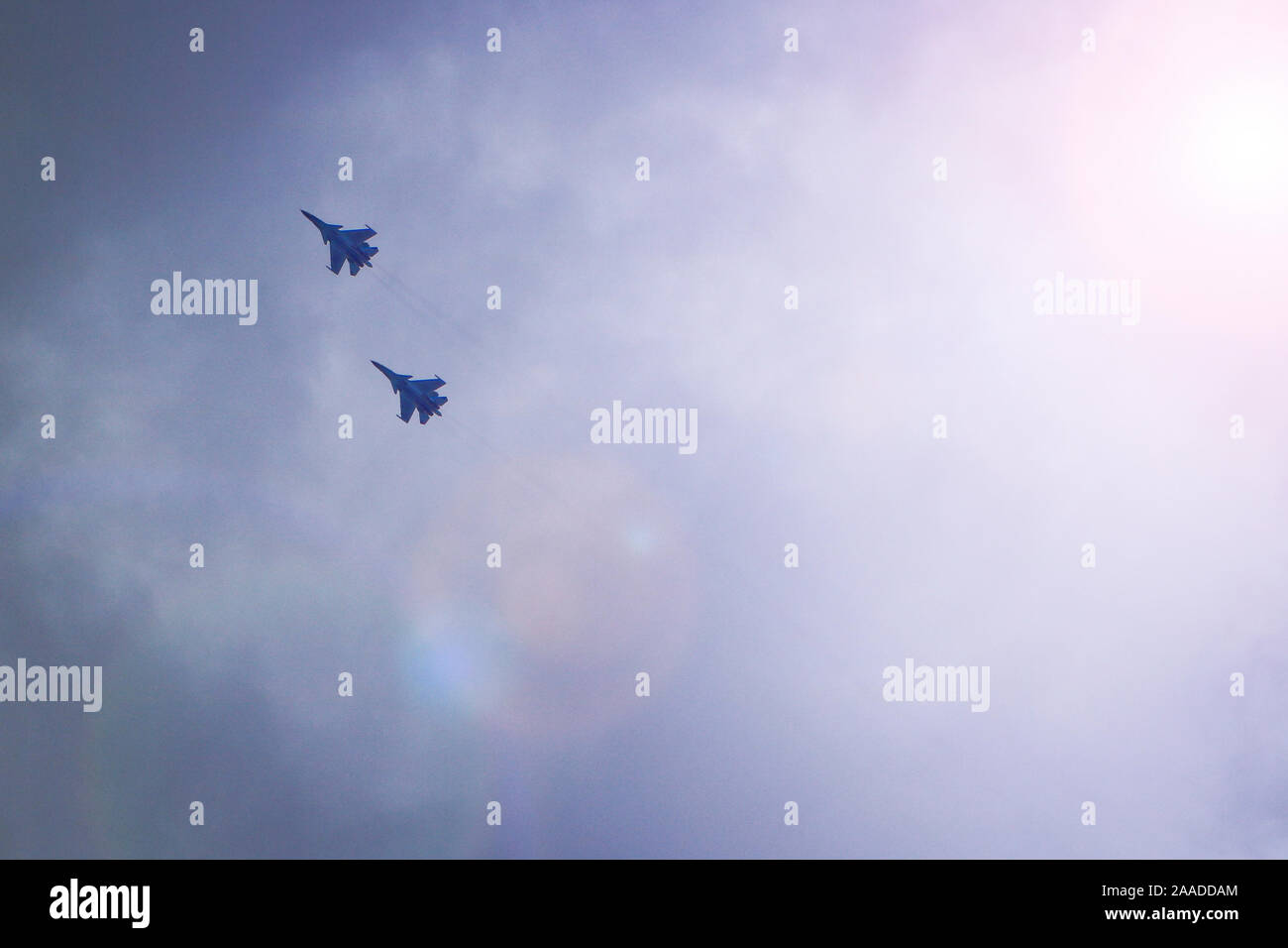 Two military fighters fly in the sky. Behind them stretches a condensation trail. Stock Photo