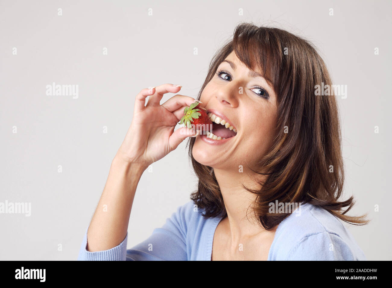 Eine junge Frau ist eine Erdbeere |  a young woman eati a strawberry, portrait Stock Photo