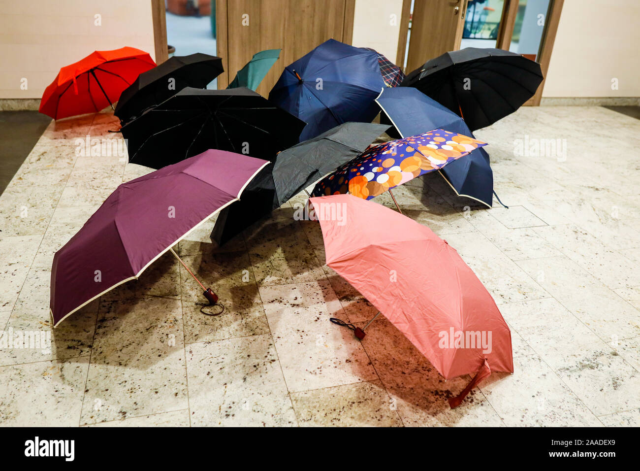 Umbrellas laid to dry outside the entrance of an office, in a modern building, during a rainy day. Stock Photo