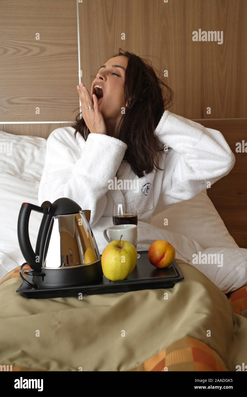 Junge muede Frau mit Fruehstueck im Bett, gaehnt, Stock Photo