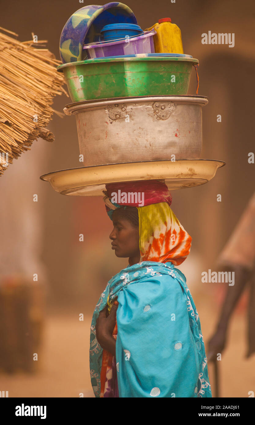 Ouled Rachid tribeswoman carying bowls and buckets on her head, Kashkasha village near Zakouma National Park, Chad, 2010. Stock Photo