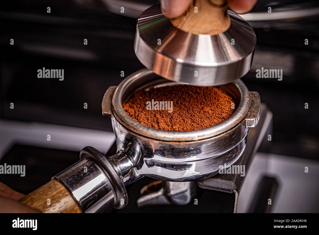 Barista is using a tamper to press freshly ground morning coffee Stock Photo