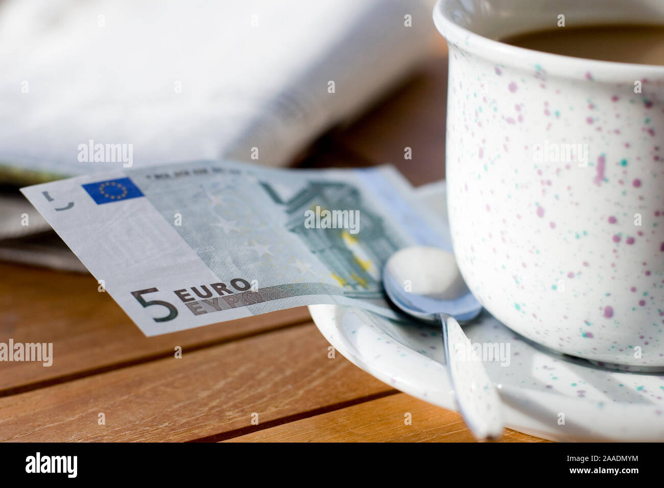 fünf Euroschein an einer Kaffeetasse Stock Photo