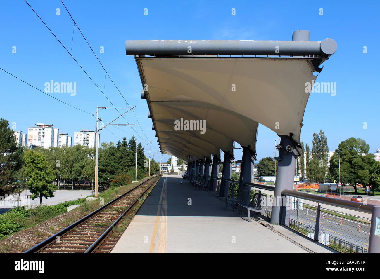 Modern train station with strong cover over benches and metal fence  surrounded with dense and old apartment buildings on warm sunny summer day  Stock Photo - Alamy