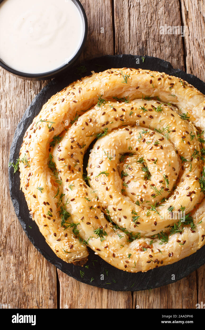 Traditional Balkan pie borek (burek) with feta served with yogurt close-up on the table. Vertical top view from above Stock Photo