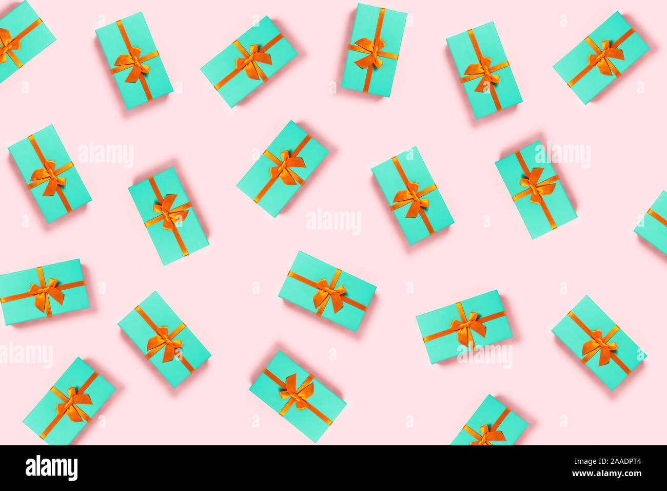 Pattern with orange bow on a mint boxes located on pink background. Stock Photo
