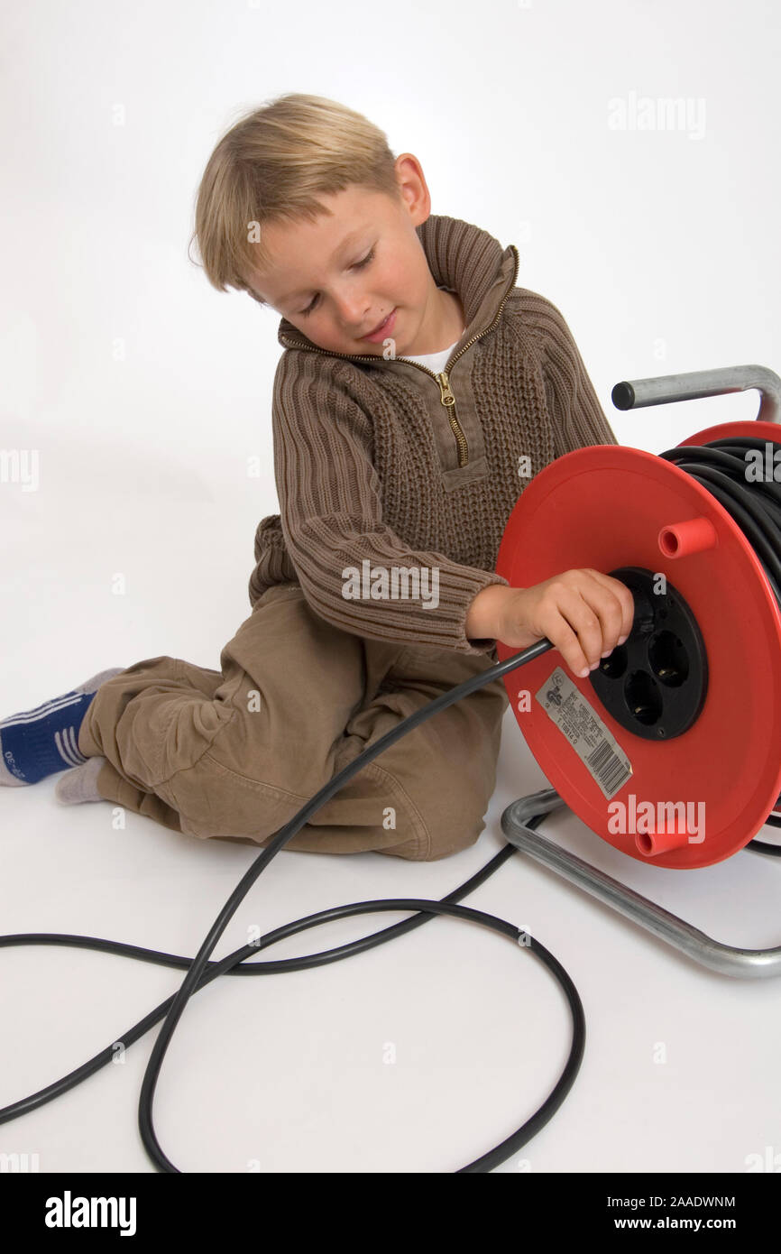 sechsjähriger Junge spielt mit Stromkabel und Kabeltrommel Stock Photo