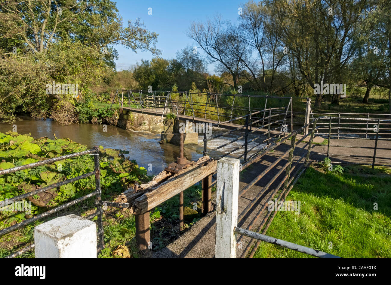 Last remains of old wooden screw of Thirsk mill and narrow footbridge over the  sluice gates at Cod Beck Thirsk North Yorkshire England UK United King Stock Photo