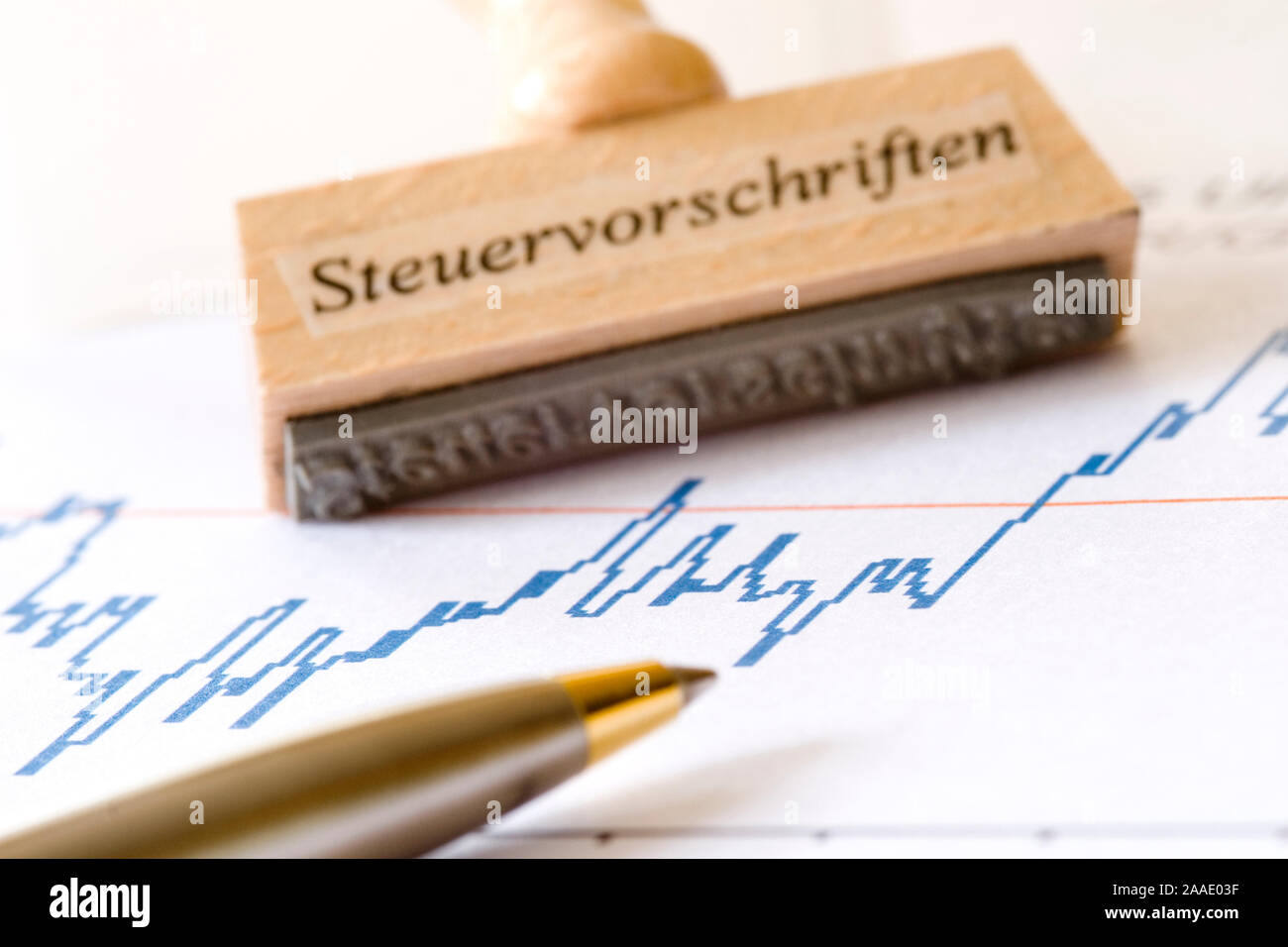 Stempel mit Aufschrift Steuervorschriften hängt über einem Wertpapierkursverlauf (Chart) Stock Photo