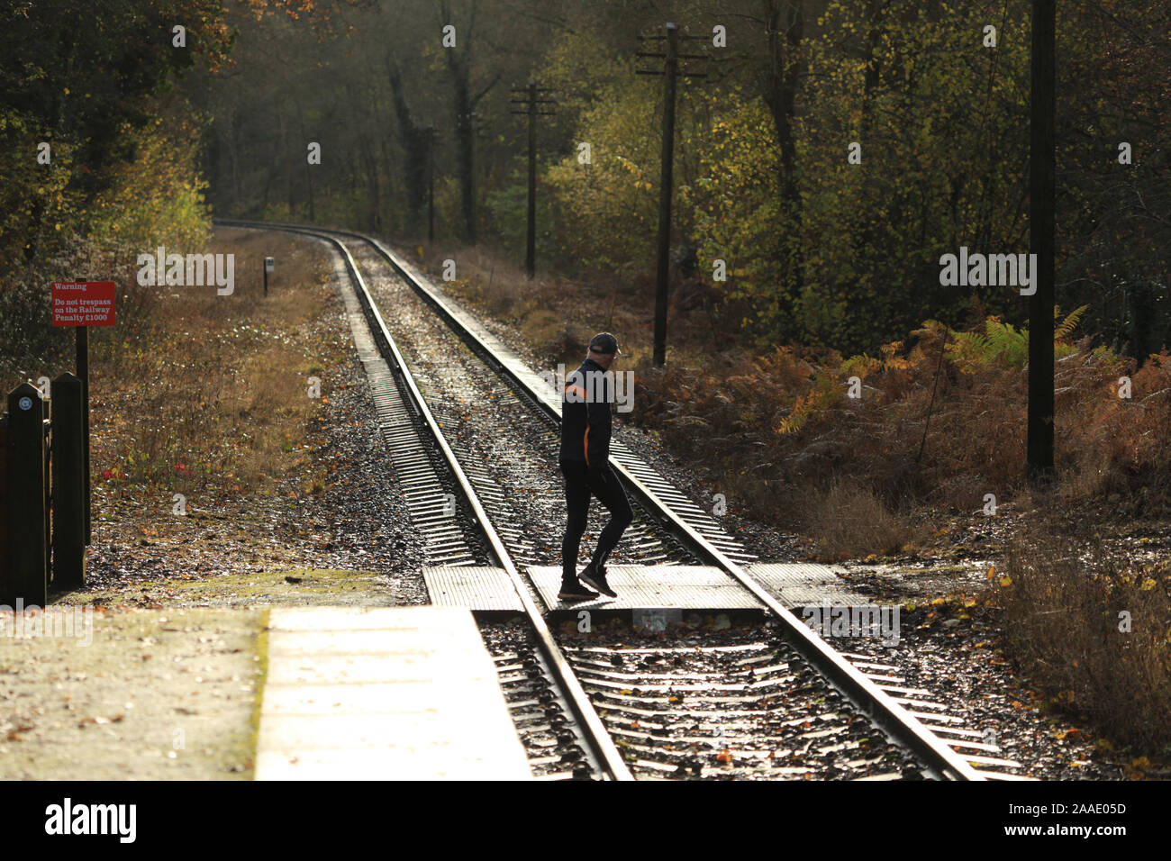 Man using a railway line crossing point in the English countryside. Stock Photo