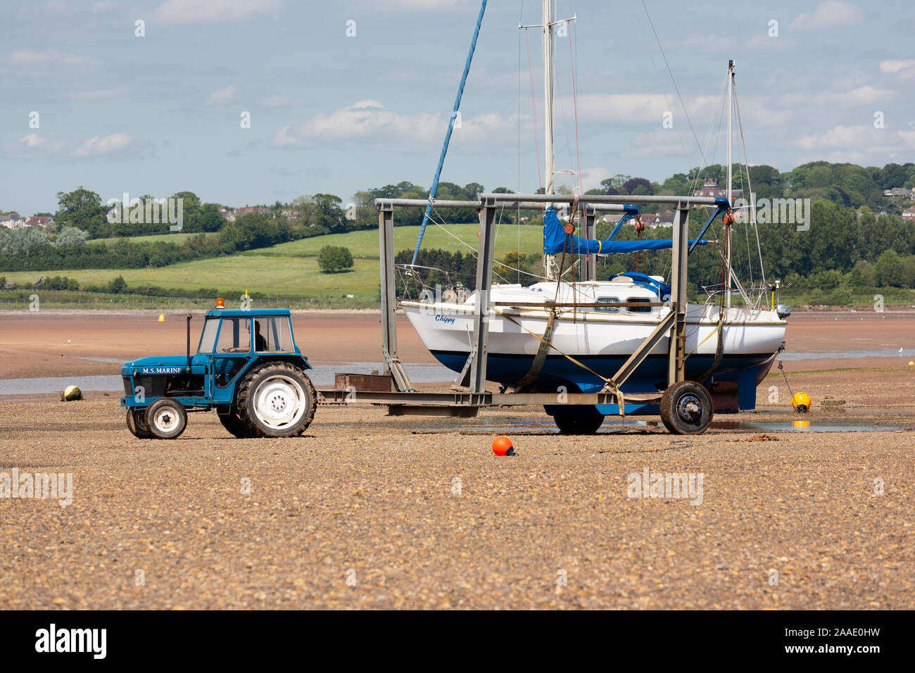 Exmouth, Devon, yacht being towed across the estuary shore by a tractor Stock Photo