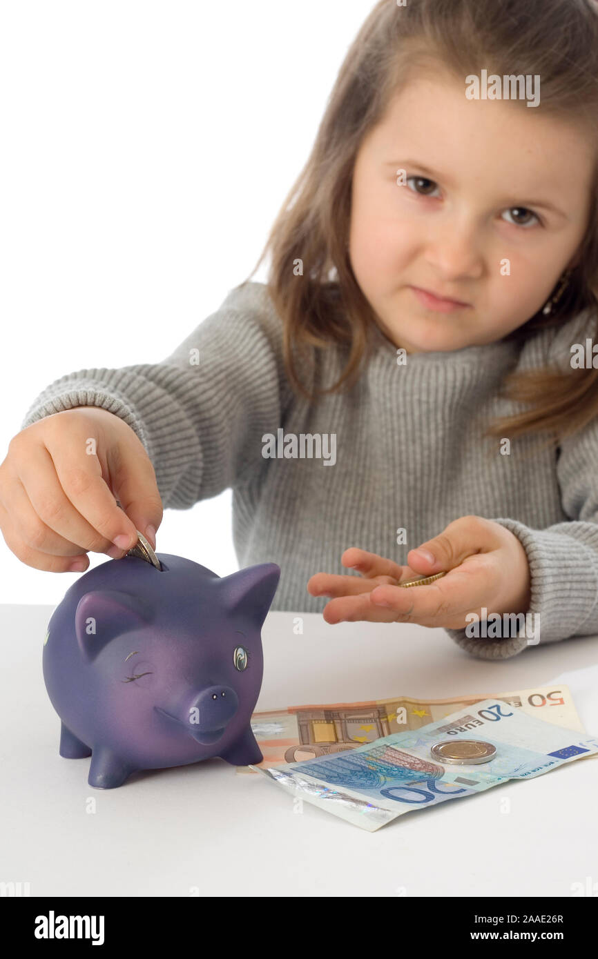 Mädchen steckt Münzen in ein Sparschwein (mr) Stock Photo