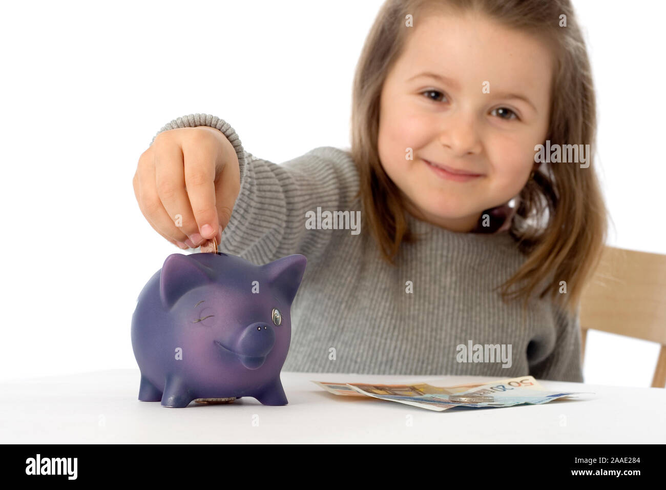 Mädchen steckt Münzen in ein Sparschwein (mr) Stock Photo