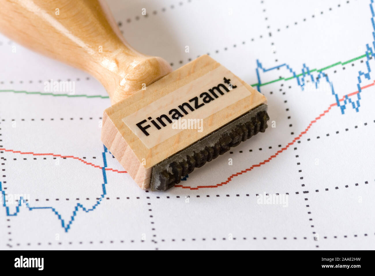 Stempel mit Aufschrift Finanzamt hängt über einem Wertpapierkursverlauf (Chart) Stock Photo
