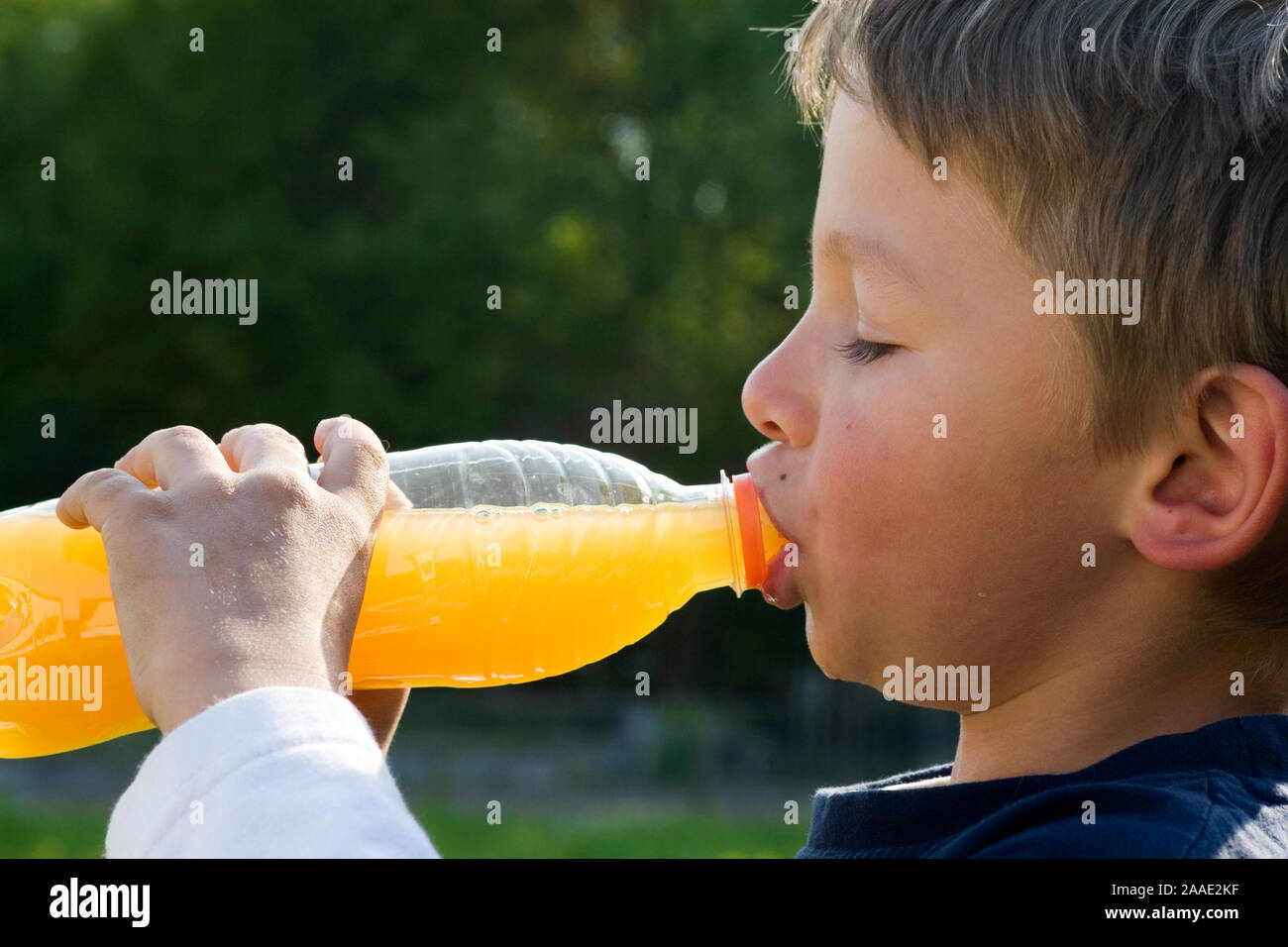 siebenjähriger Junge trinkt aus einer Flasche (mr) Stock Photo