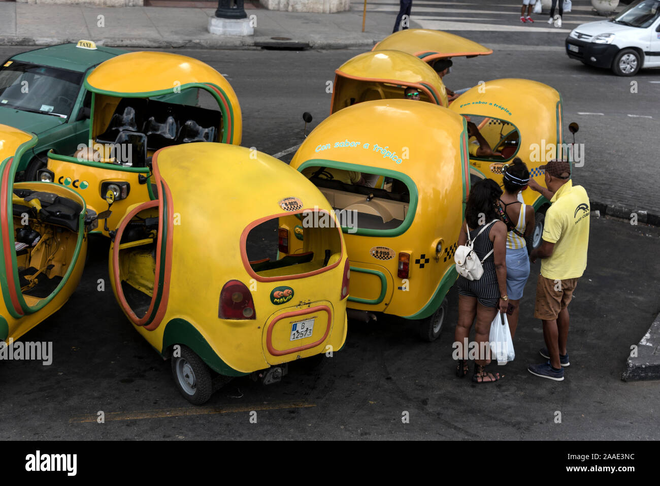 A small fleet of yellow Cocotaxi in a parking space in Havana's old town ( Habana Vieja) in Cuba.  The Cocotaxi, a familiar sight in the streets, first Stock Photo