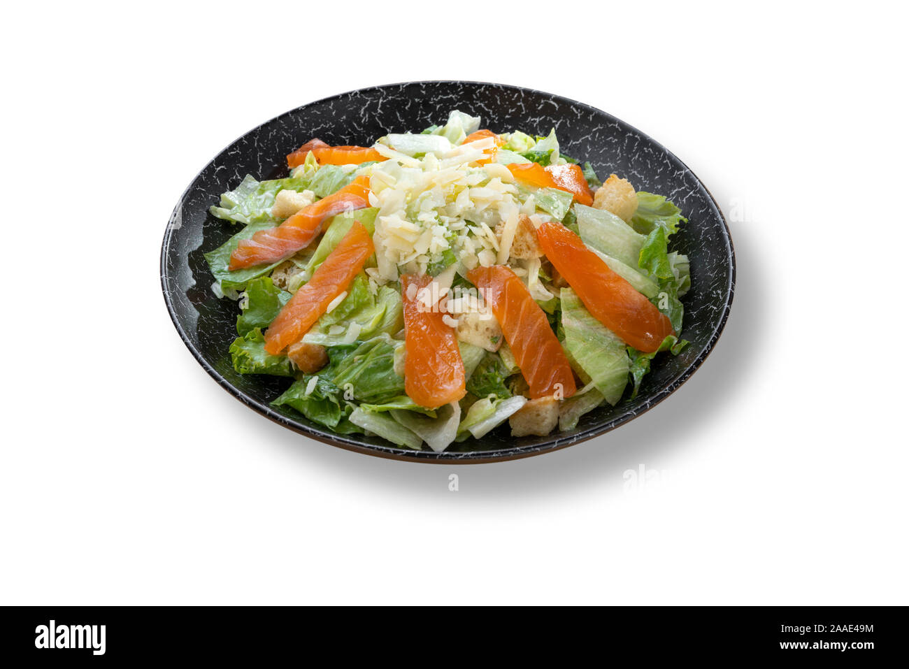 Fresh salad caesar with salmon and parmesan in beautiful black modern plate Stock Photo