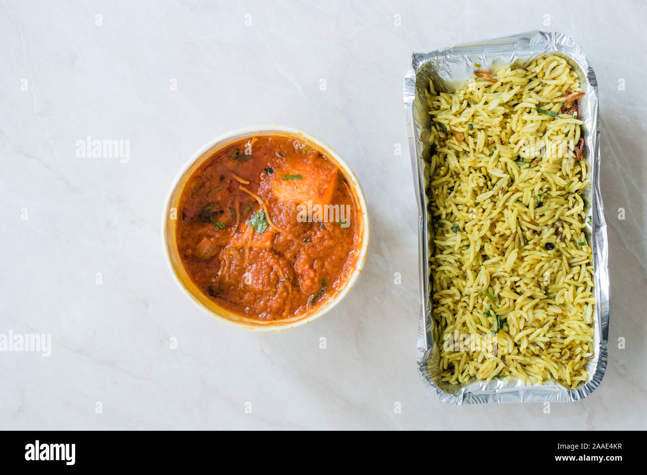 Take Away Indian Food Paneer Butter Tikka Masala / Cheese Cottage Curry and Jeera Zira Rice Basmati Pilaf or Pilav in Plastic Box Package / Container. Stock Photo