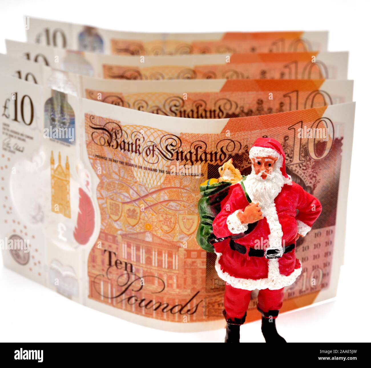 A santa claus figurine standing in front of some new ten pound notes.England UK Stock Photo