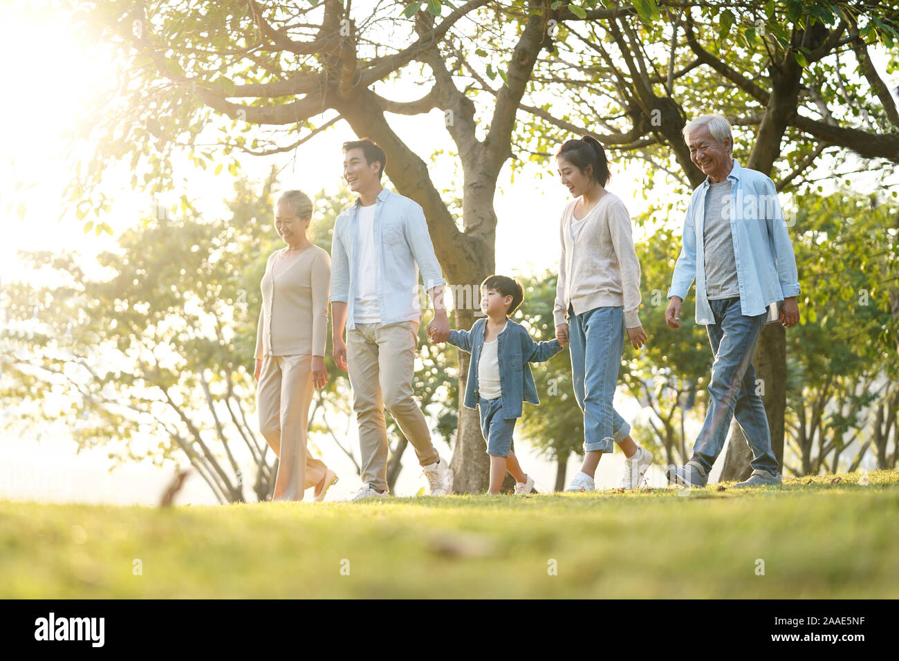 three generation happy asian family walking outdoors in park Stock Photo