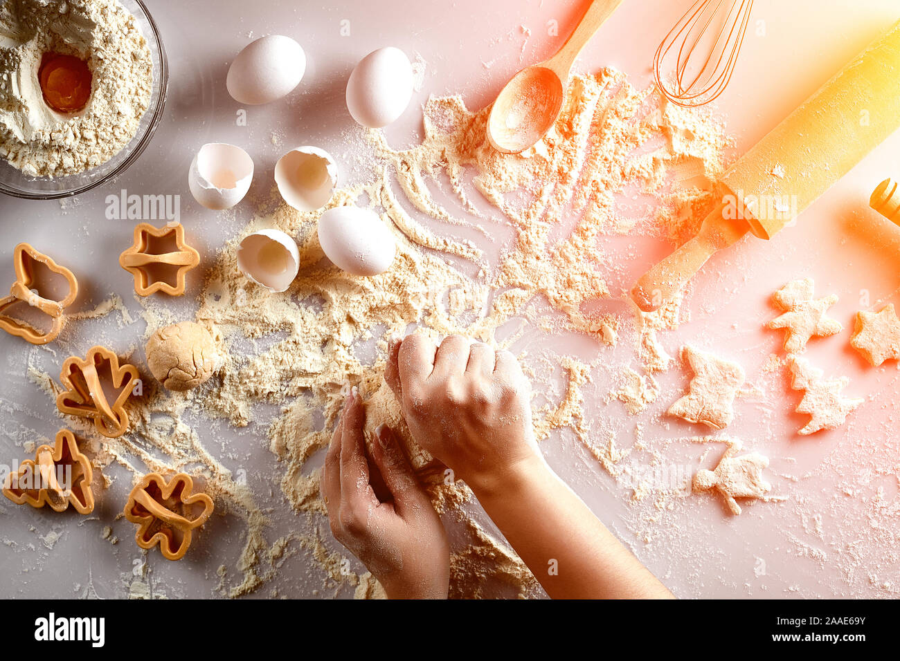 Female hands knead dough with egg and a rolling pin for preparation of