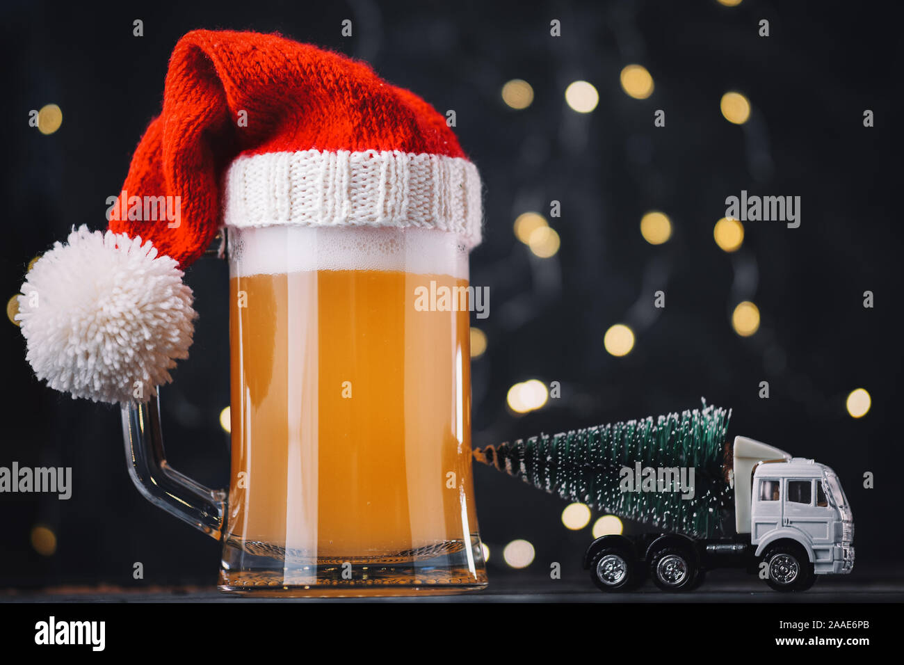Christmas beer ale mug in Santa hat on dark background with bokeh garland. Craft beer Stock Photo