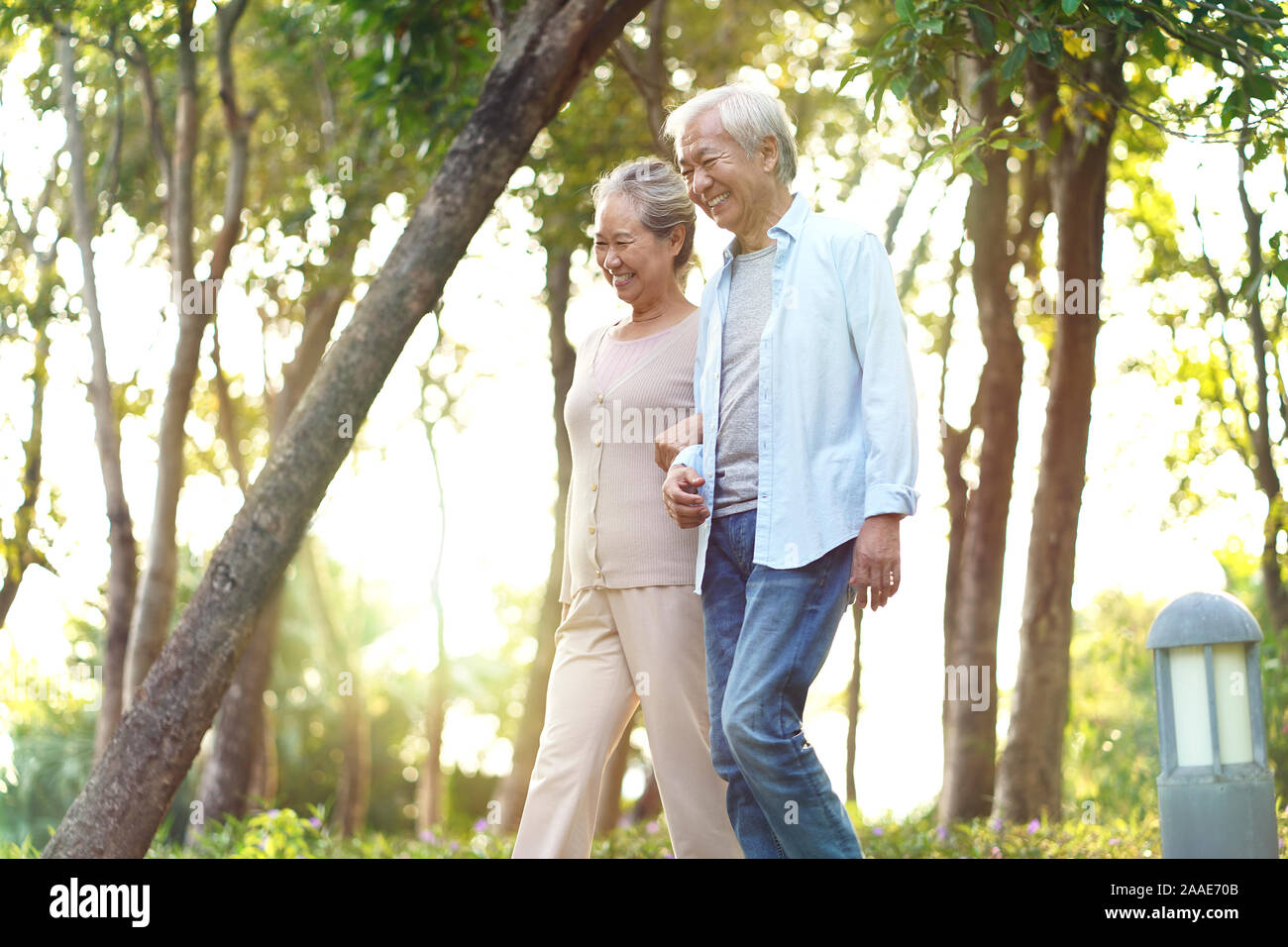 happy senior asian couple walking talking relaxing outdoors in park Stock Photo