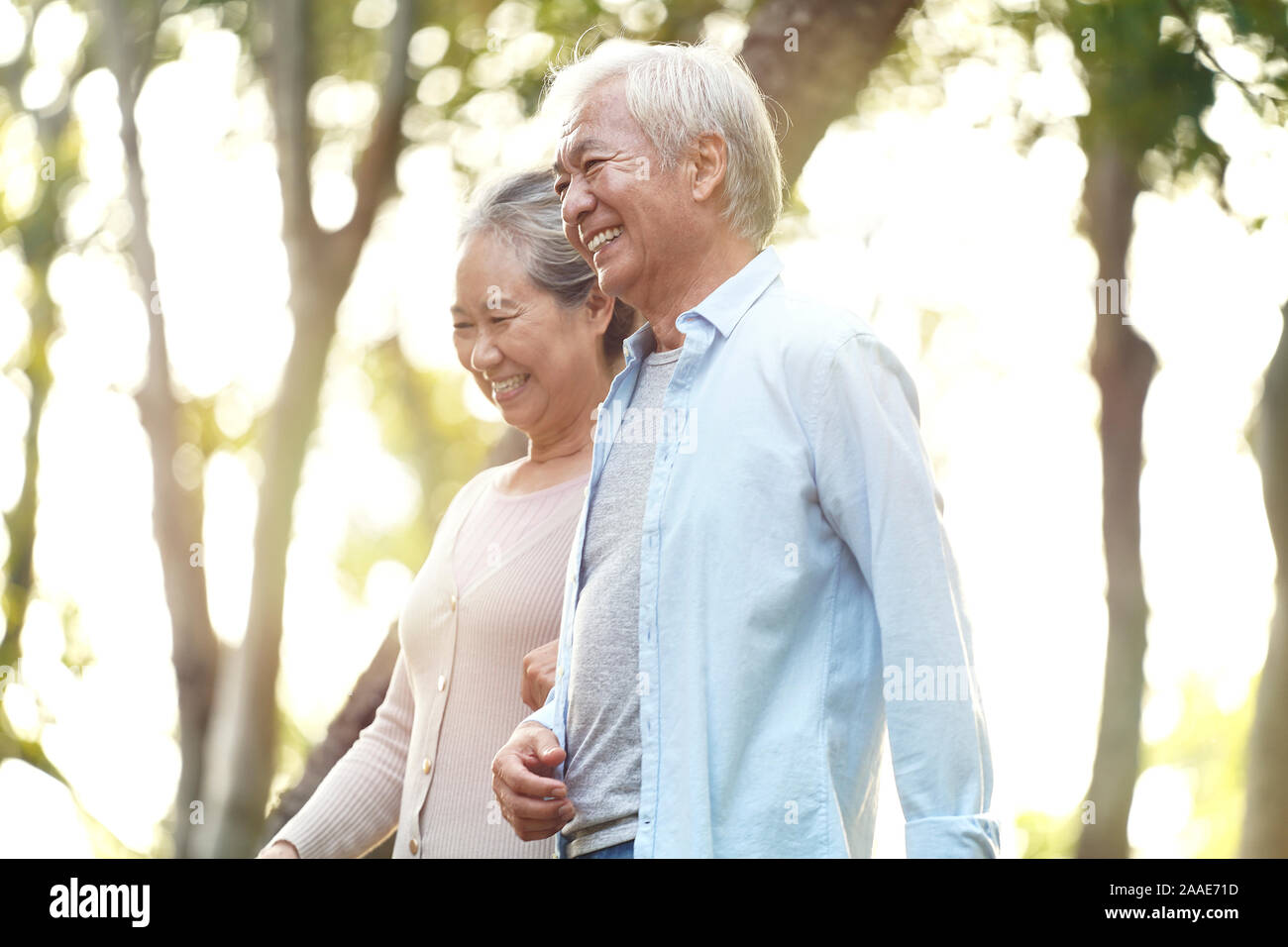happy senior asian couple walking talking relaxing outdoors in park Stock Photo