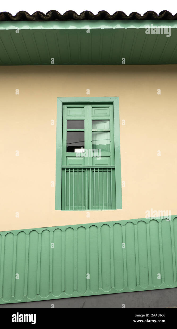 Facade with window, roof and sloping base in green and beige colors, traditional architecture of