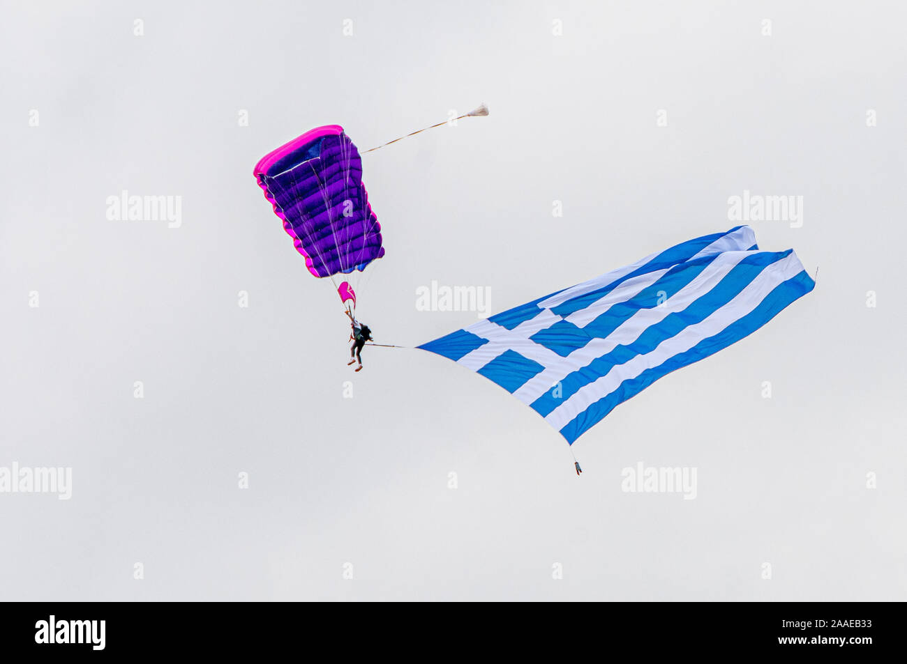 Unrecognized Greek paratrooper with parachute flying on air with a very large Greek flag Stock Photo