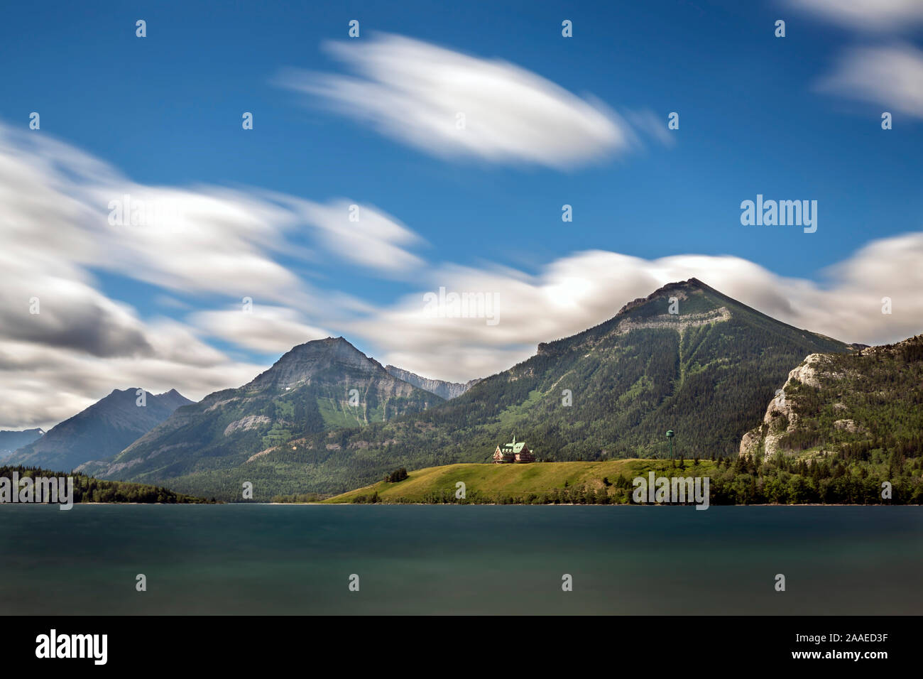 Beautiful dramatic long exposure photograph of iconic destination in Waterton Lakes National Park, historic Prince of Wales Hotel on the shore, wind Stock Photo