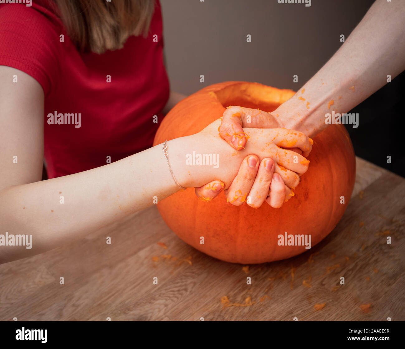 Close up of two young people shaking hands job well done after having carved a traditional Halloween pumpkin Stock Photo