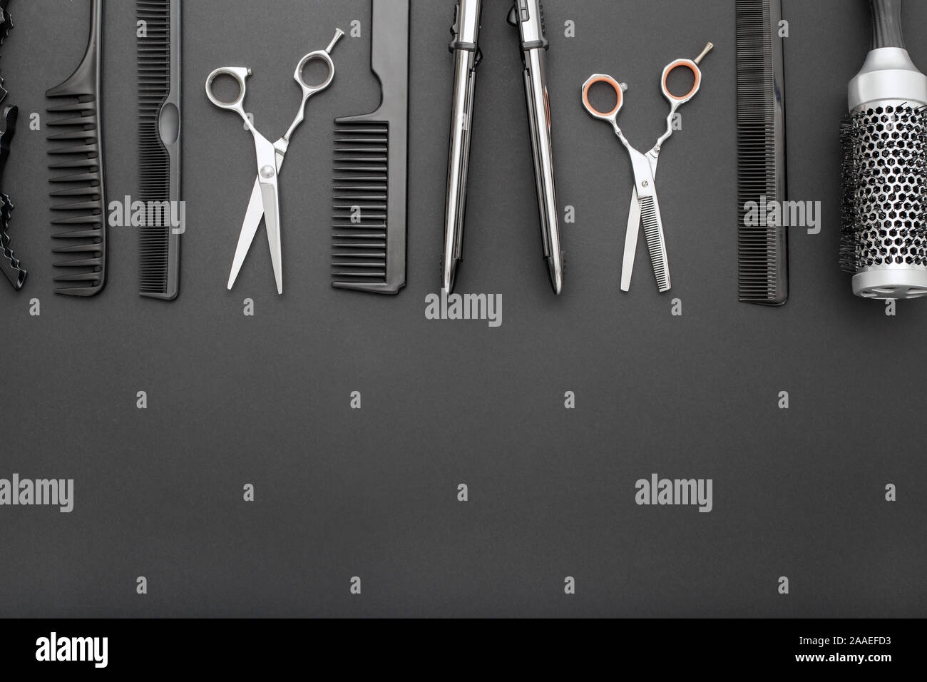 Flat lay composition with Hairdresser tools: scissors, combs, hair iron on black background with copy space for text. Frame. Hairdresser service Stock Photo