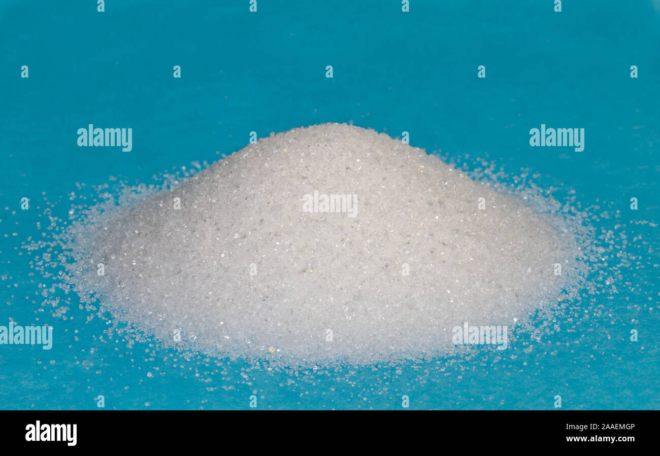 Heap of white granulated sugar on a blue background Stock Photo