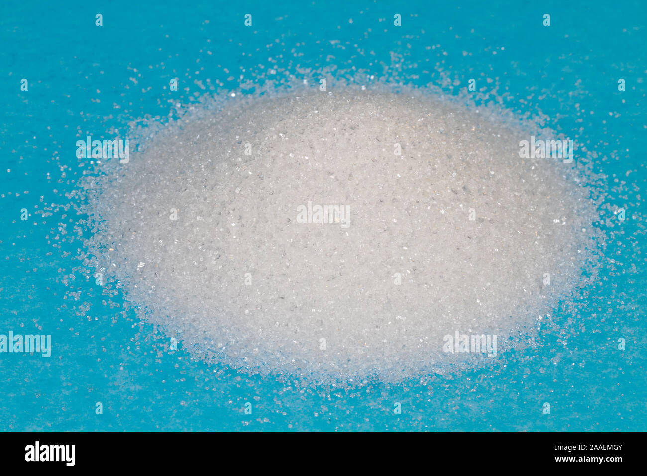 Heap of white granulated sugar on a blue background Stock Photo
