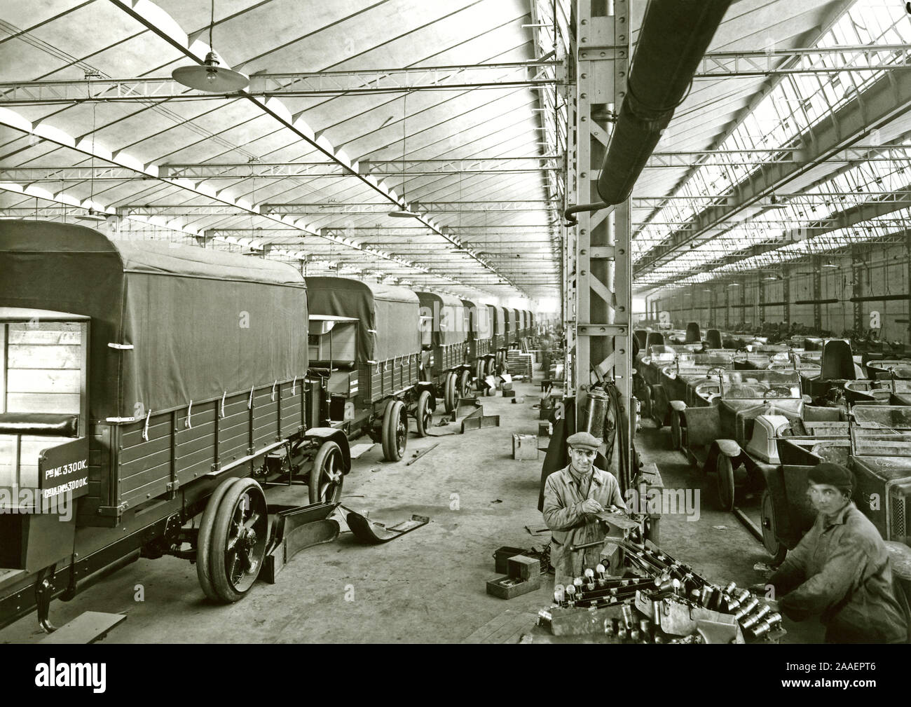 The production line at the Renault vehicle manufacturing plant at Boulogne-Billancourt, Paris, France c.1920. The company's trucks (Camions Rapide) are being assembled on the left and a production line of their convertible (soft-top) G-type cars are on the right. In the foreground two men are at a work bench, one using a file. Stock Photo